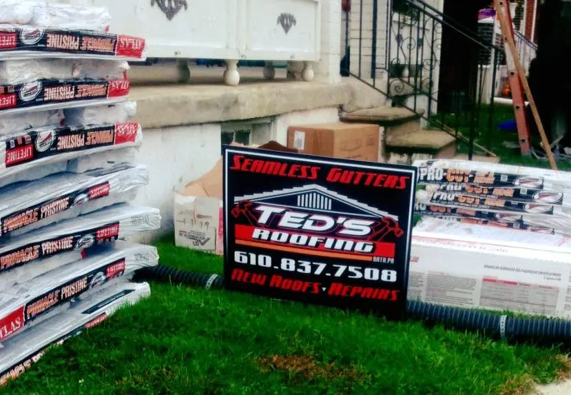 Ted's Roofing yard sign with shingle bundles
